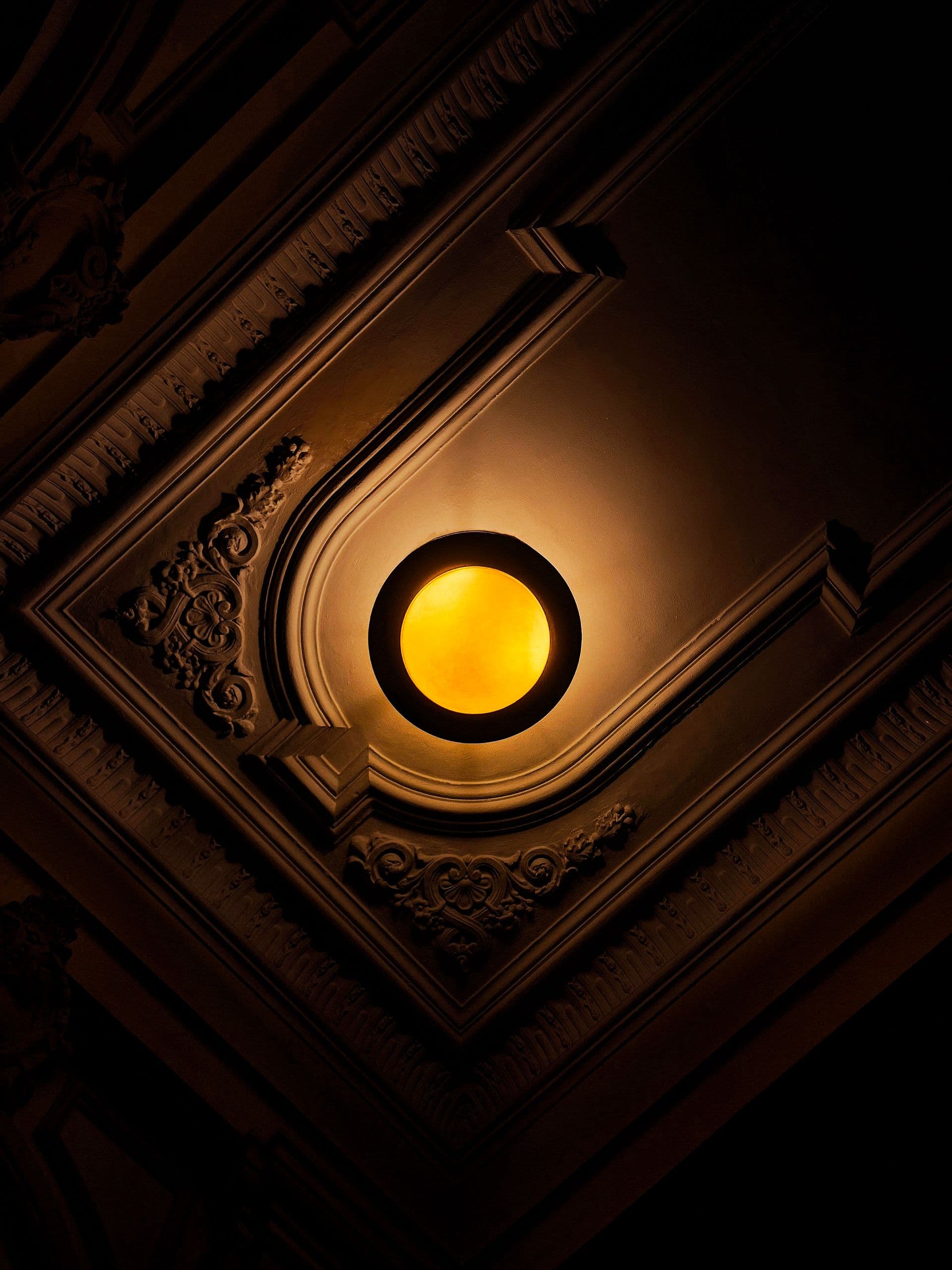 Roseta ornamentada de gesso no teto, com luminária central